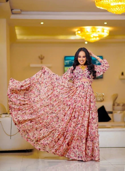A stylish pink Habesha chiffon dress with cutouts and floral details.
