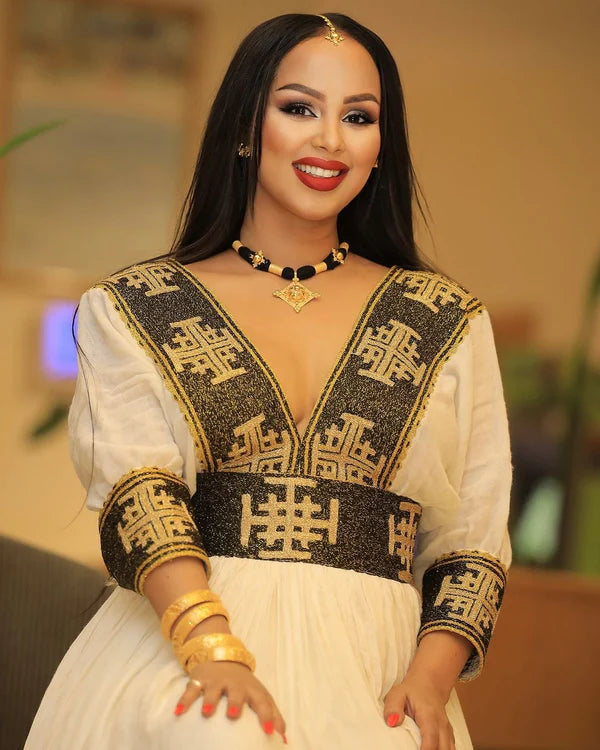 A stunning black and gold Habesha Kemis featuring intricate geometric cross embellishments