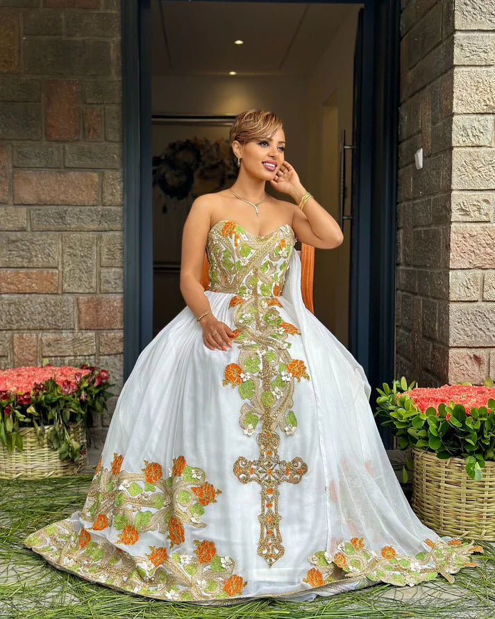 captivating green and orange Habesha dress, a masterpiece of handcrafted artistry, is adorned with delicate floral and cross-stitch embroidery.